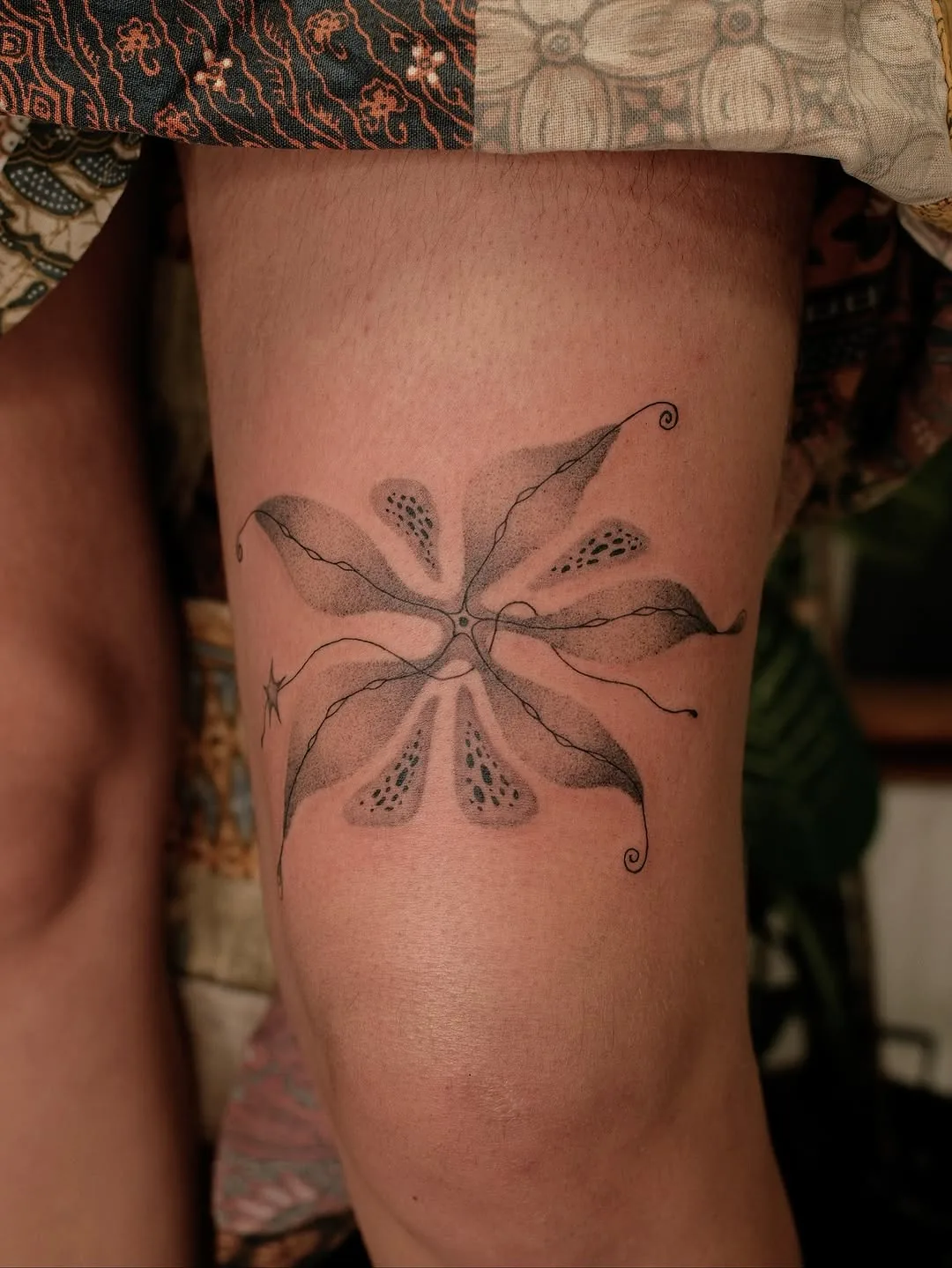 Alien flower tattoo above the knee