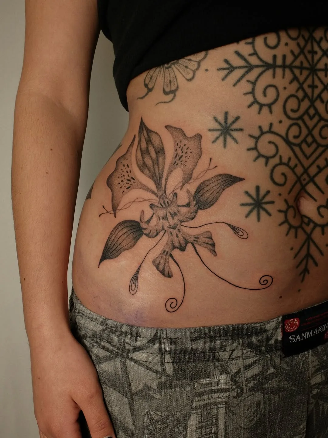 Lily with flowing tendrils tattooed on the hip